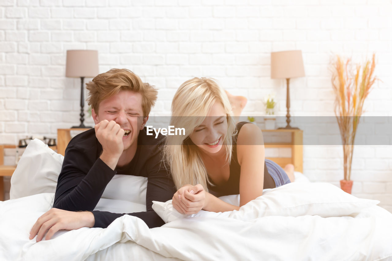 Couple laughing while lying on bed at home