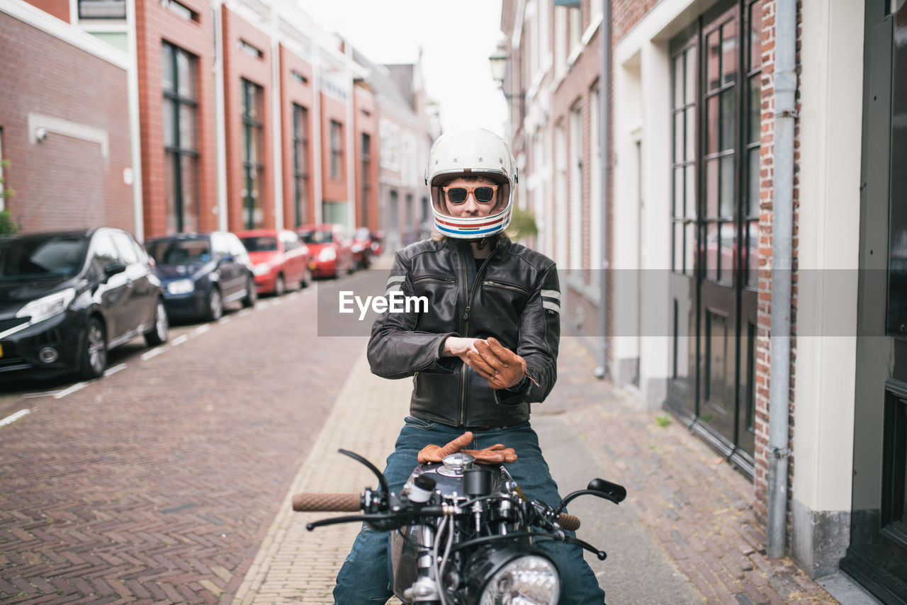 Portrait of man siting on motorcycle at street in city