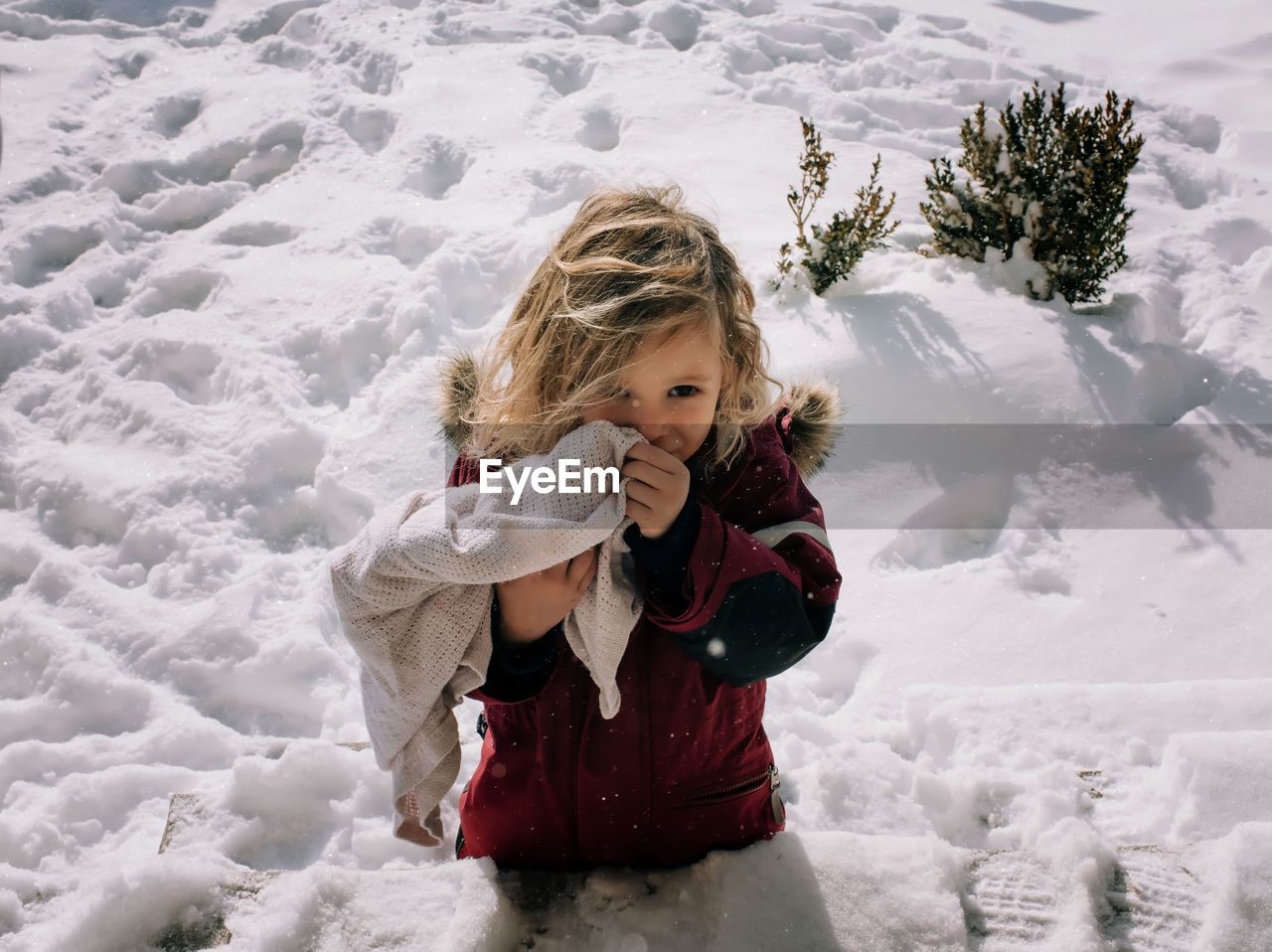 Young blonde girl standing in the snow smiling in winter