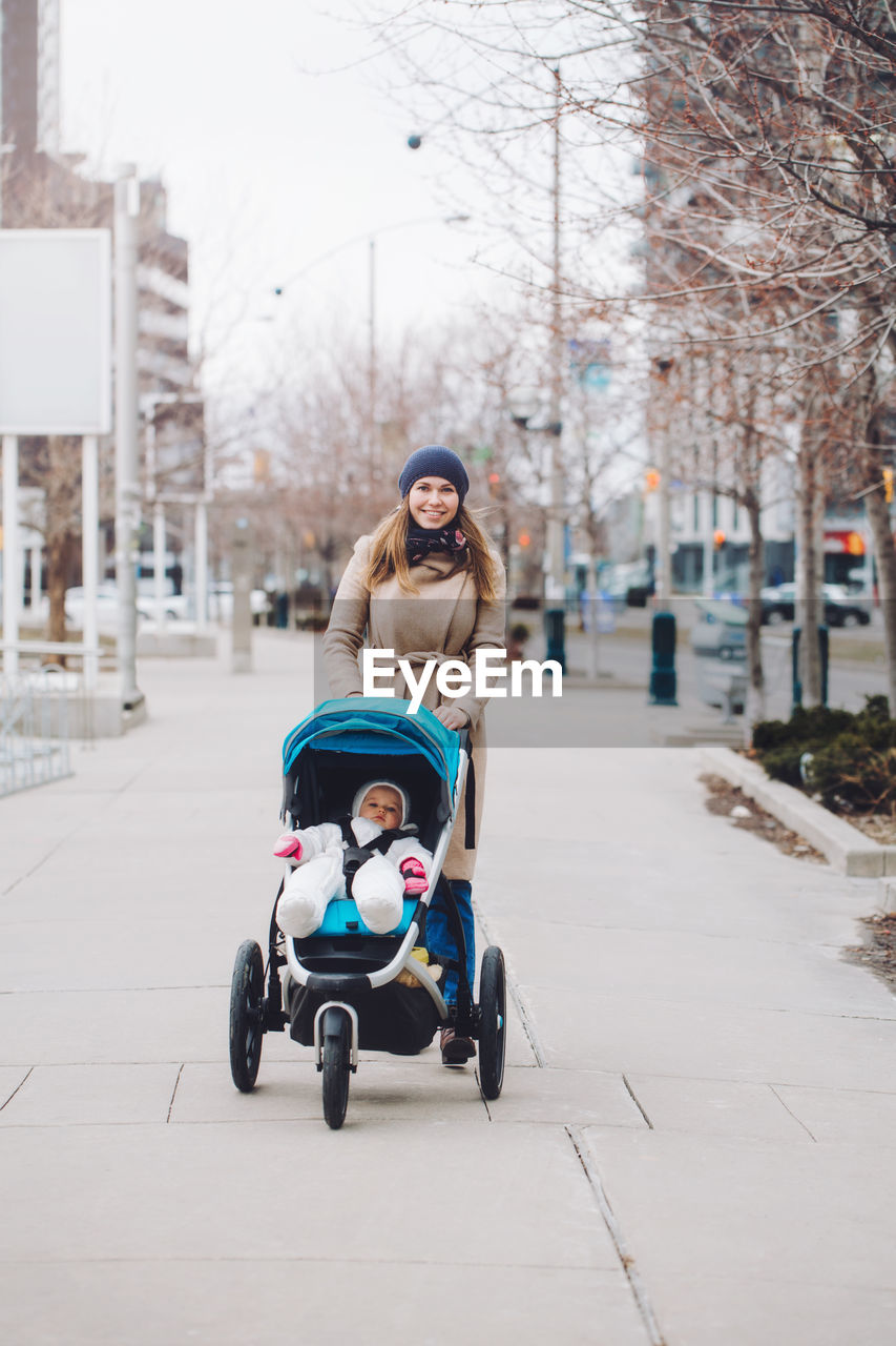 Portrait of smiling woman with baby walking on street