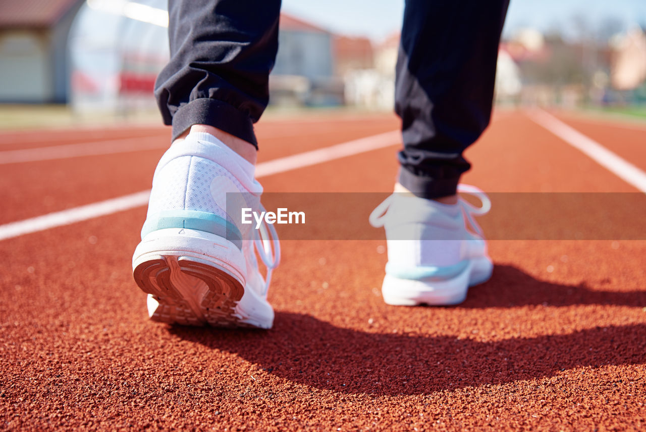 Male runner feet with white sneakers at stadium track, close up. sport sneakers for jogging