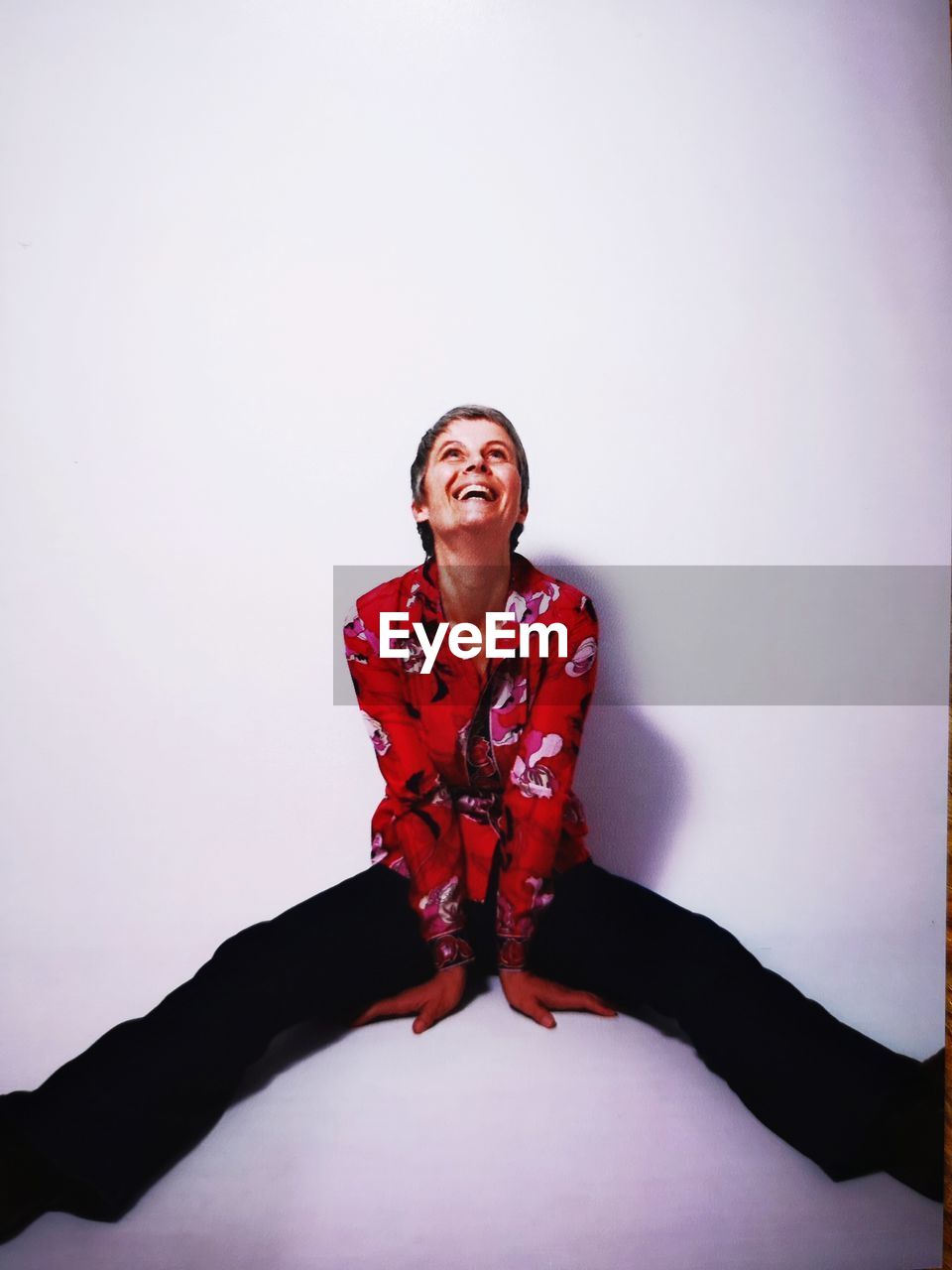 Happy woman looking up while sitting against white background