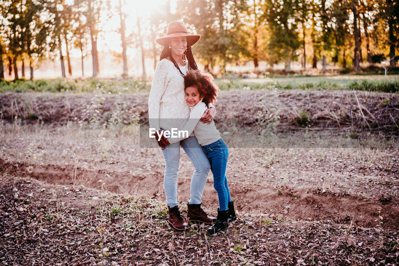 REAR VIEW OF MOTHER AND DAUGHTER STANDING ON FOOTPATH