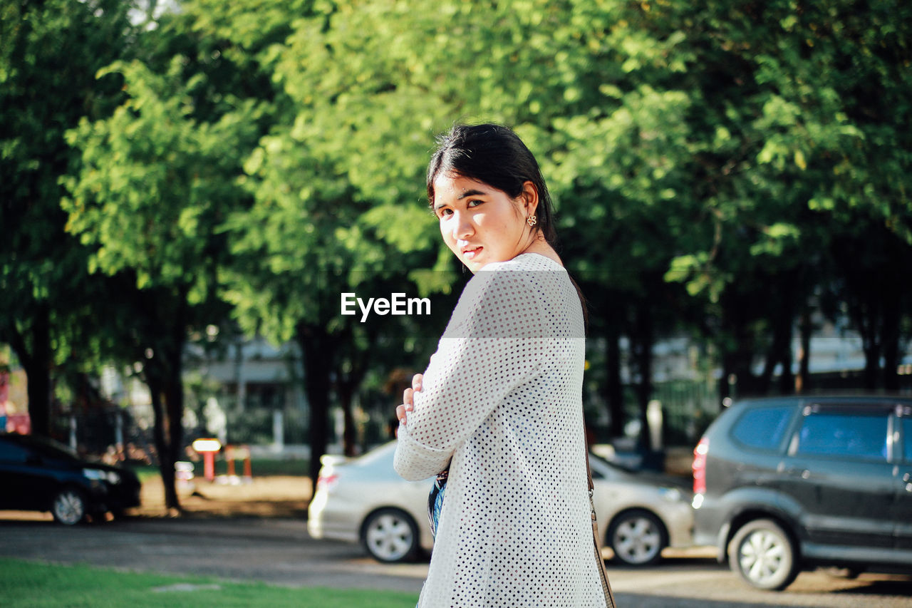 Portrait of woman against trees in city