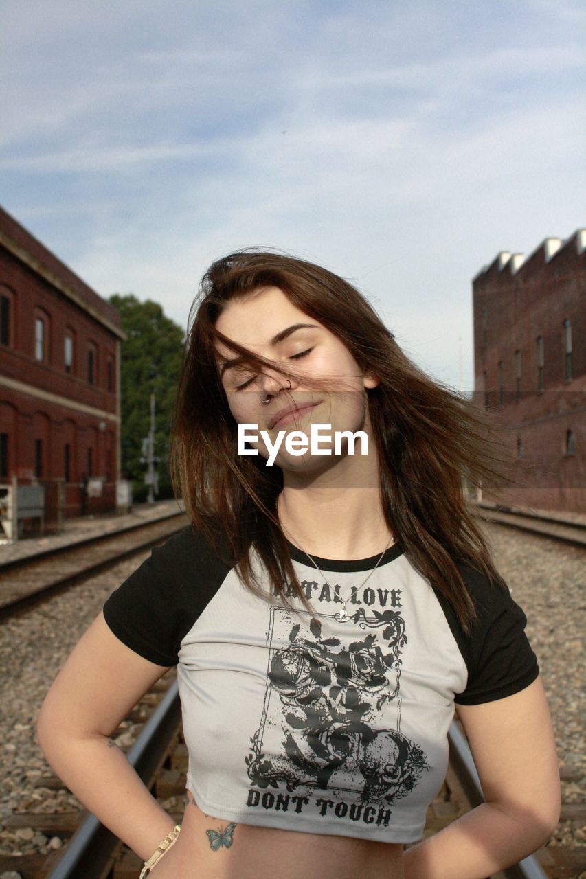 portrait of young woman standing against sky