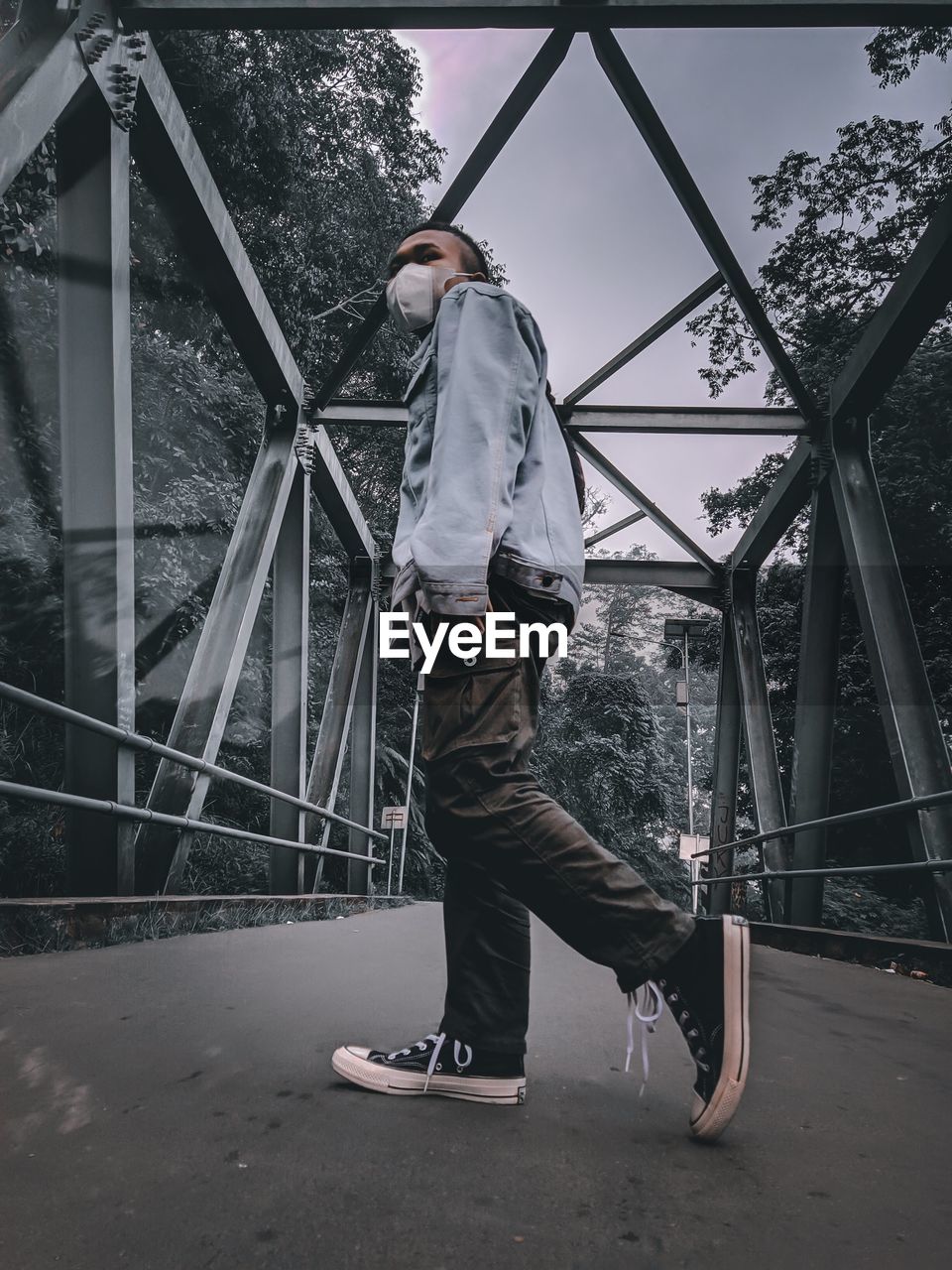 Full length of man standing on railing against trees