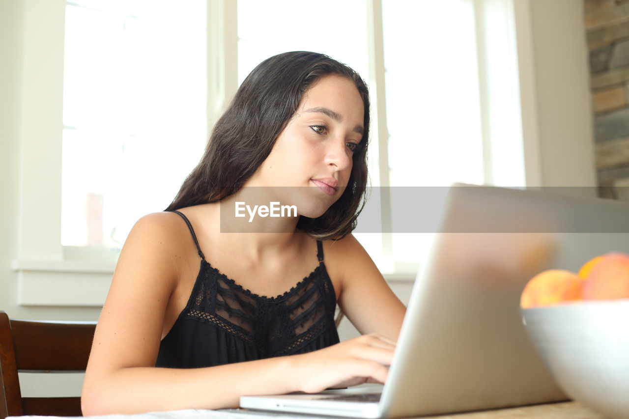 Girl using laptop by fruits on table