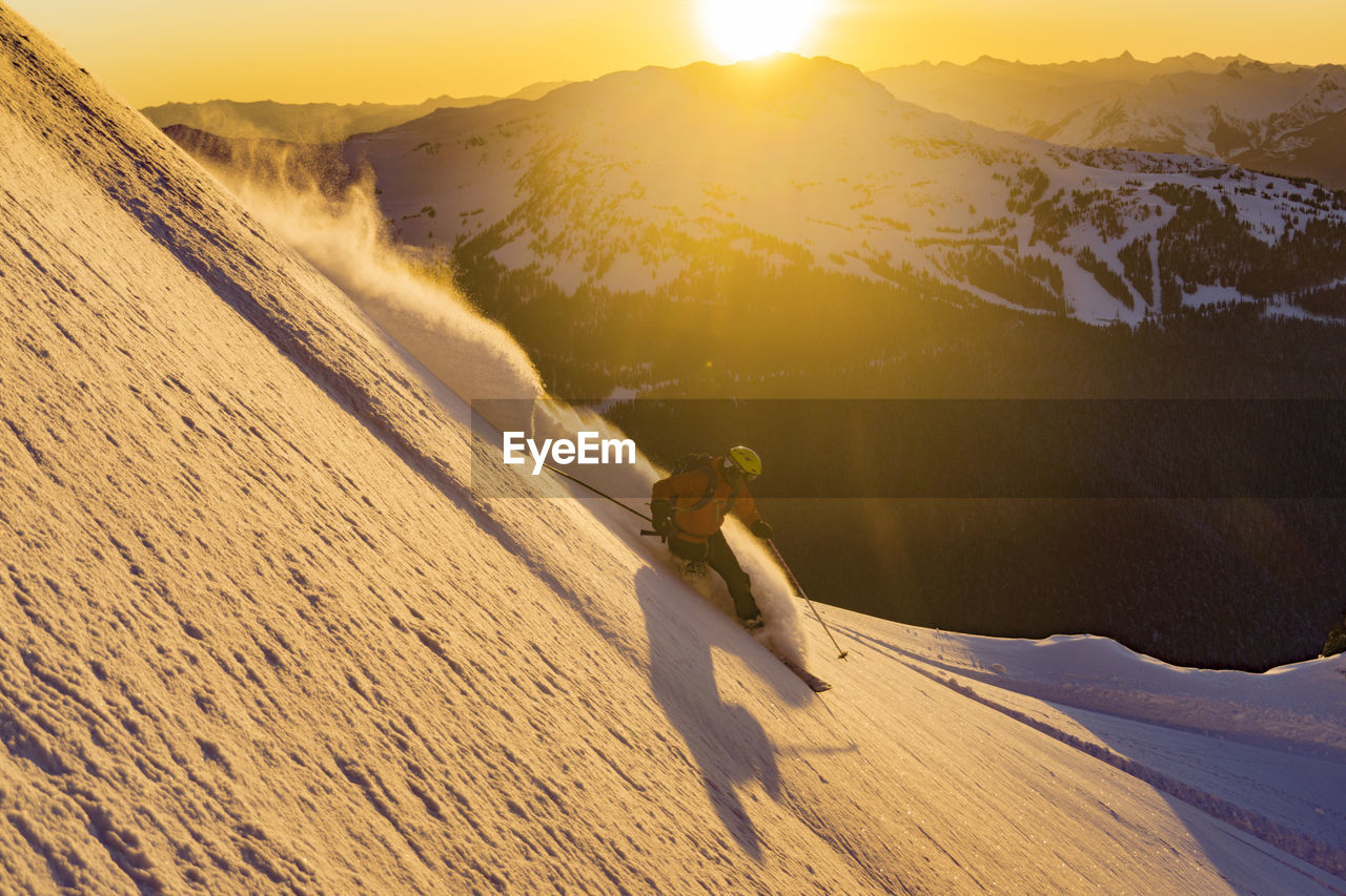 Man skiing on snow during sunset