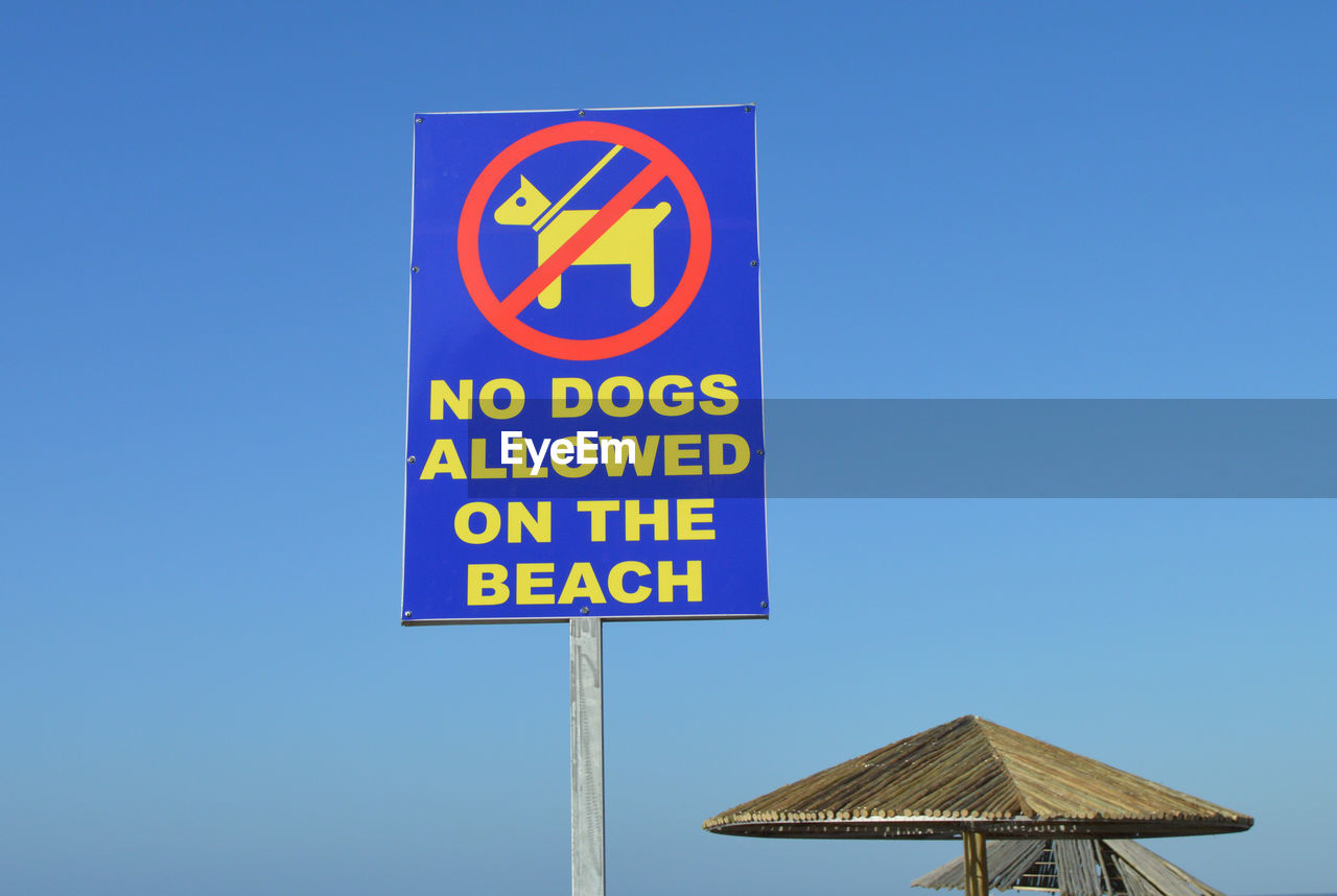 Close-up of warning sign against clear blue sky