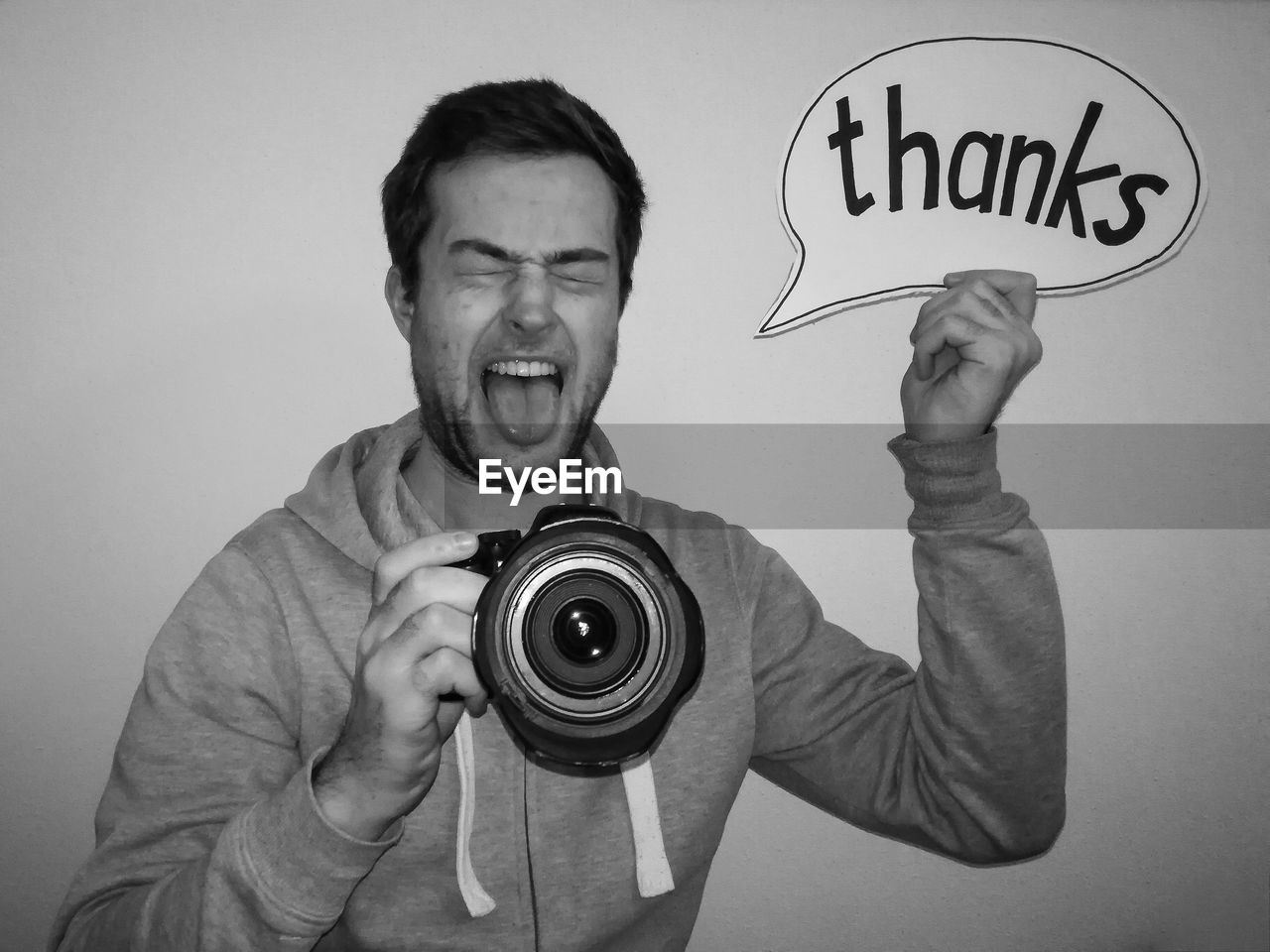 Man holding speech bubble with thanks text while photographing by white background
