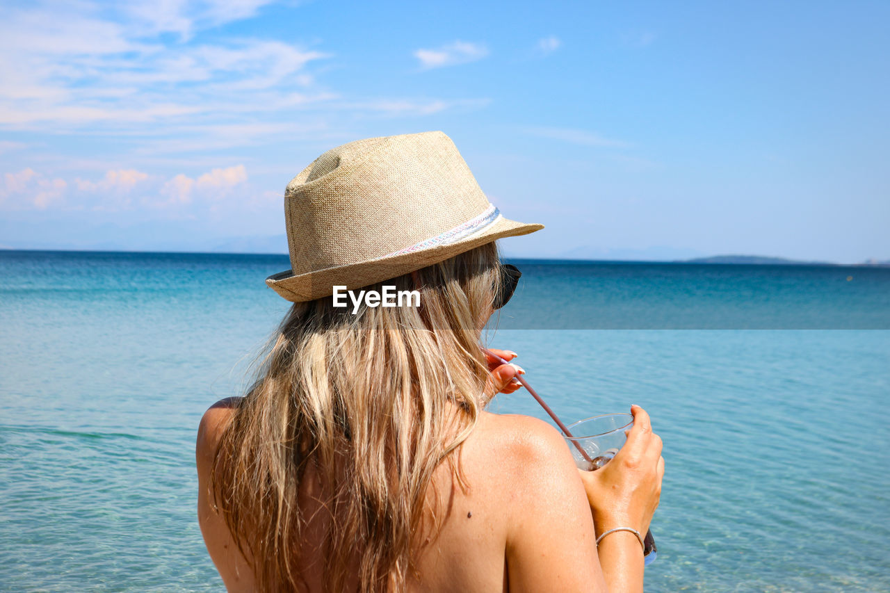 Rear view of woman wearing hat against sea