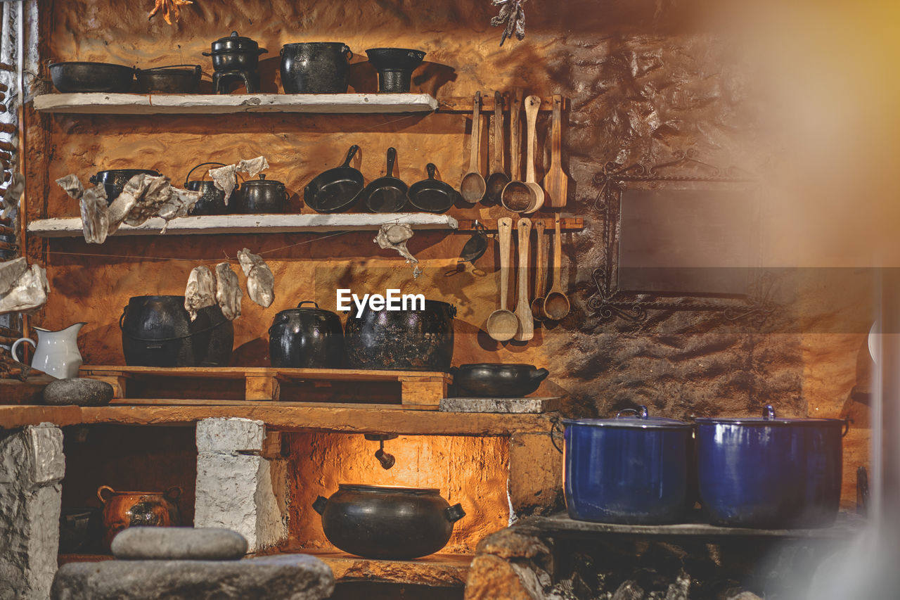 Cast iron pot with fresh herbs, spices and kitchen utensils for tasty cooking on rustic table.