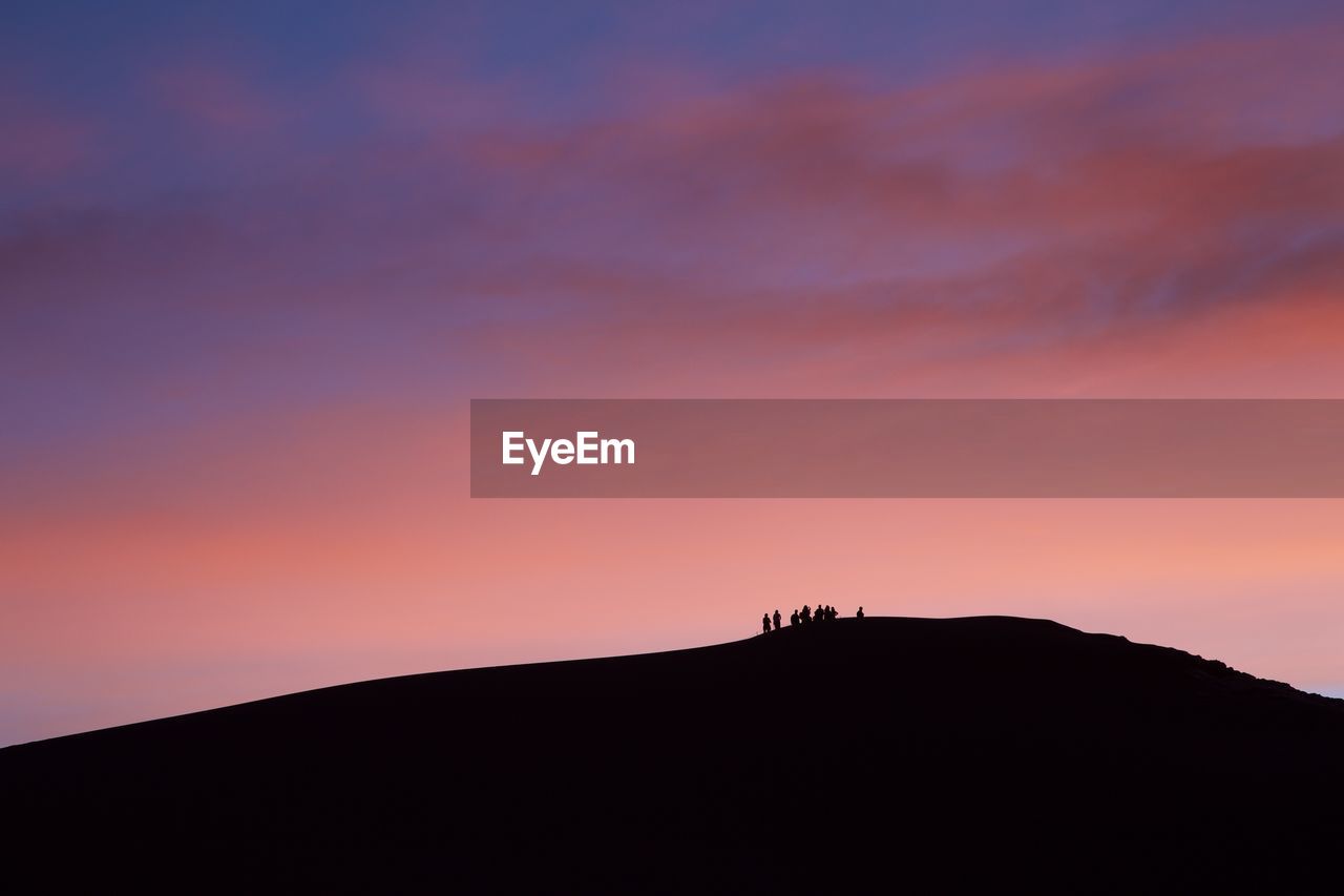 Silhouette people on mountain against sky during sunset