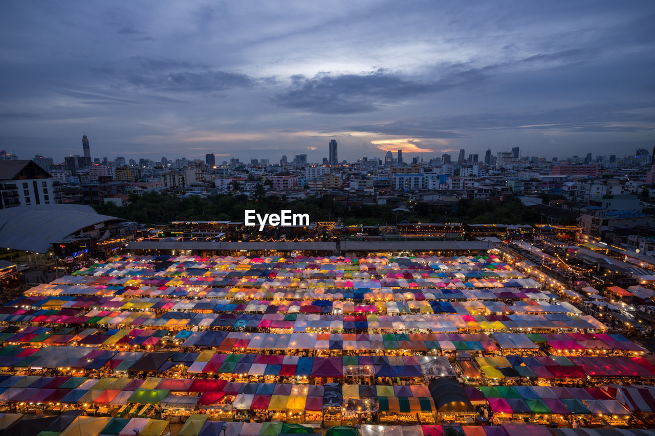 High angle view of illuminated city buildings against sky at sunset