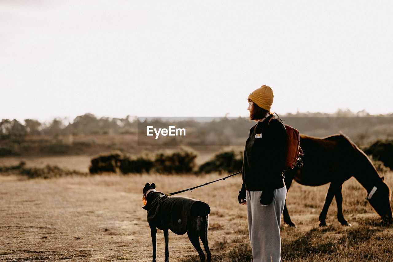 Woman with dog standing of field