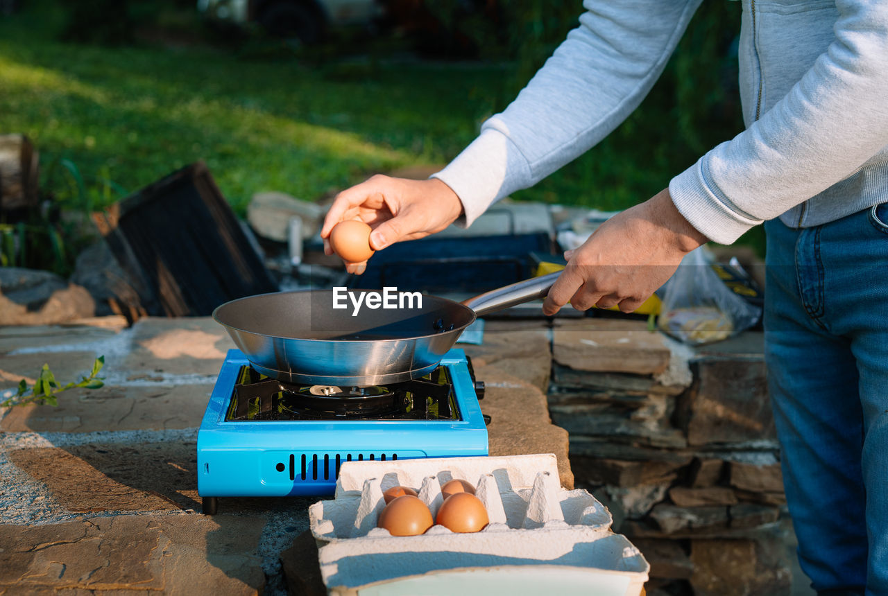 Midsection of man preparing food on camping stove