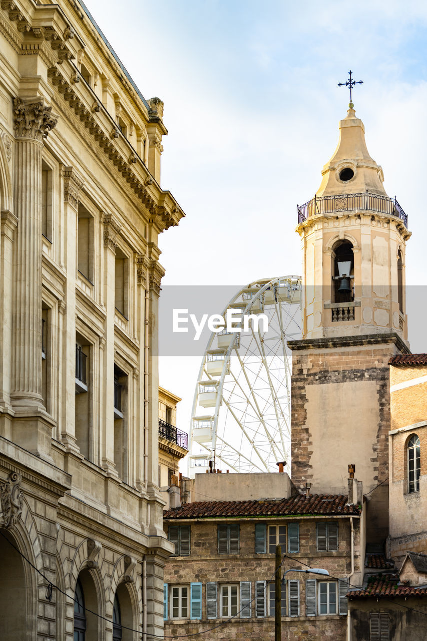 The bell tower of the church of saint ferreol and observation wheel at marseille vieux port, france