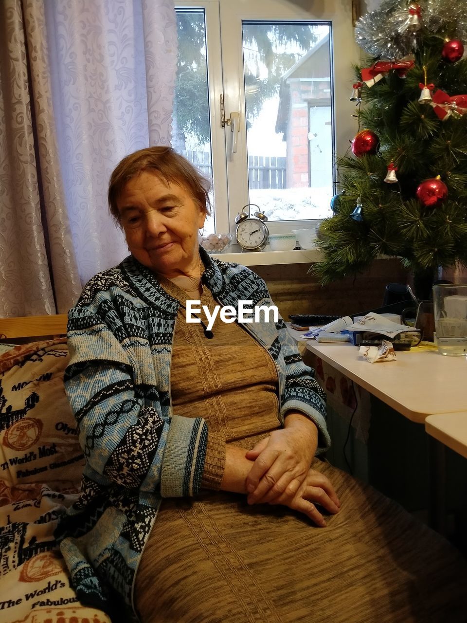 PORTRAIT OF A SMILING WOMAN SITTING AT HOME