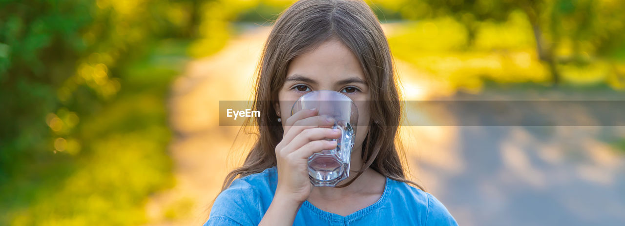 Portrait of girl drinking water at park