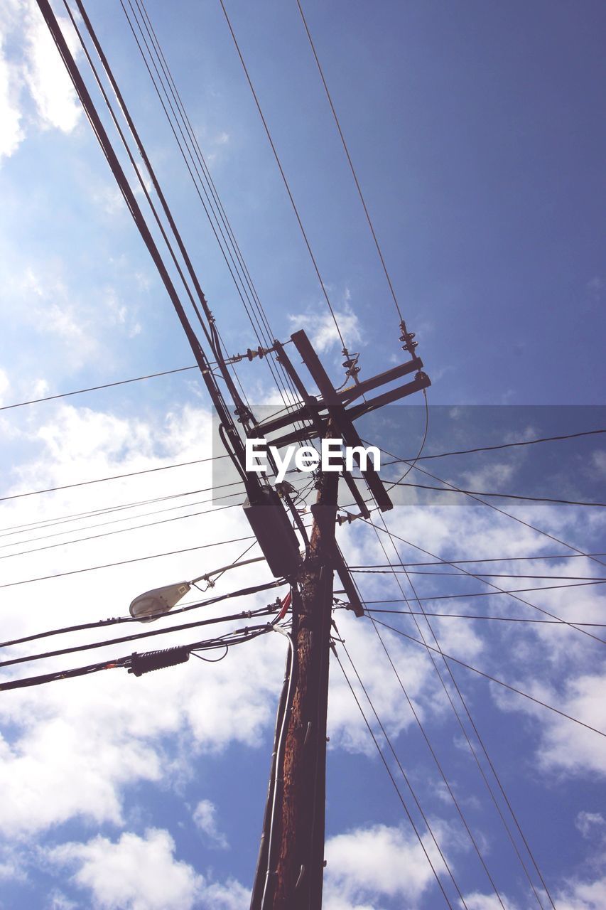 Low angle view of telephone pole against cloudy sky