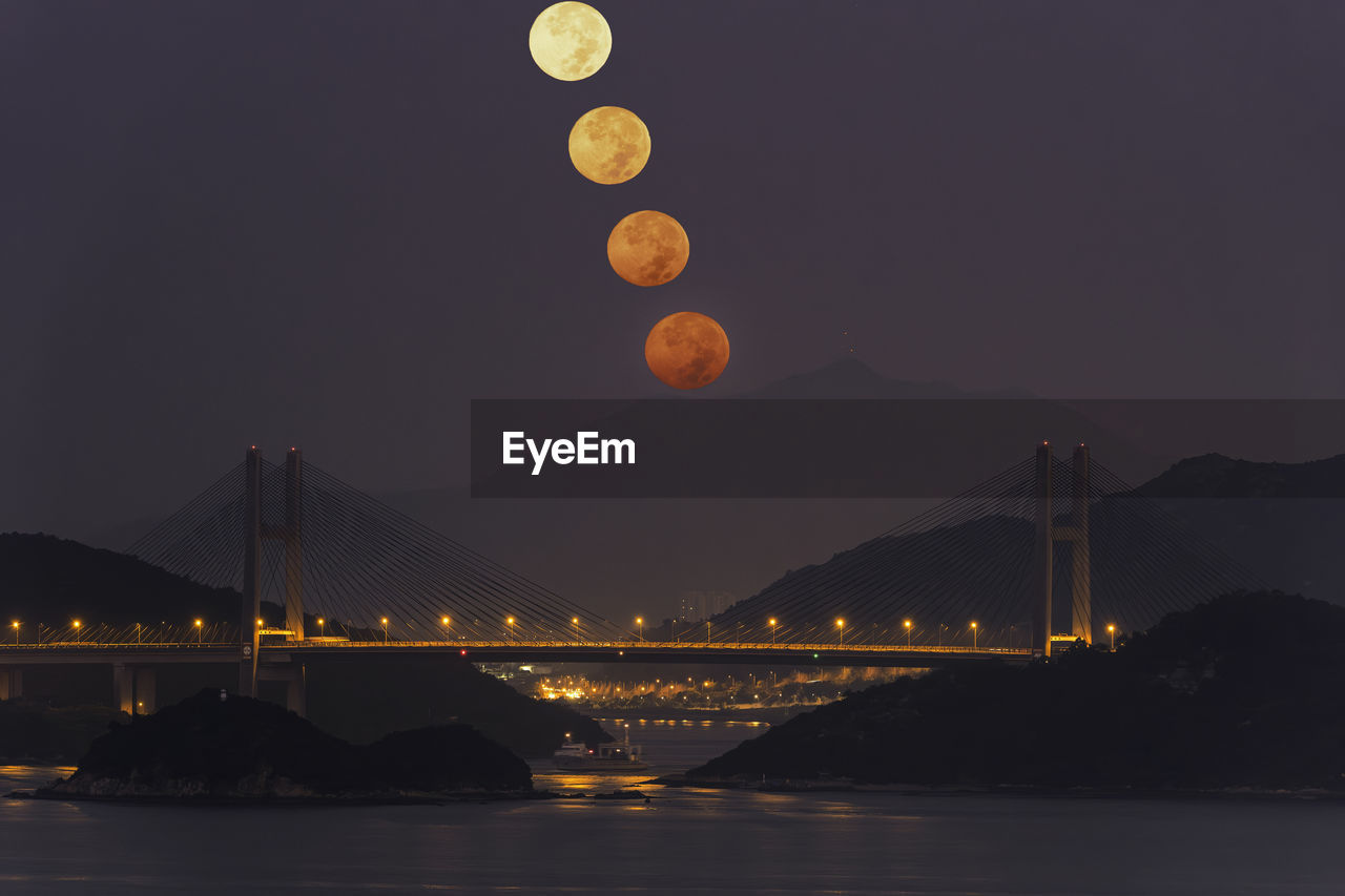 Illuminated bridge over river at night