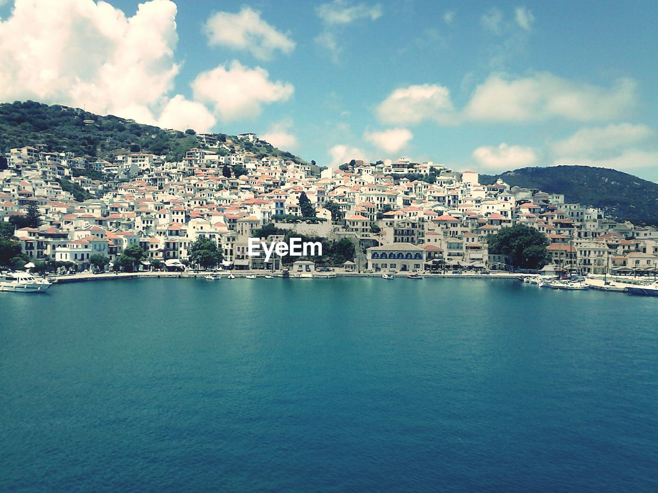 View of cityscape by sea against sky