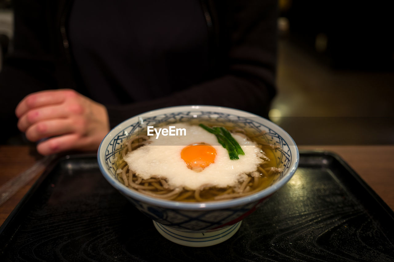 High angle view of noodles served with egg in bowl on table at home