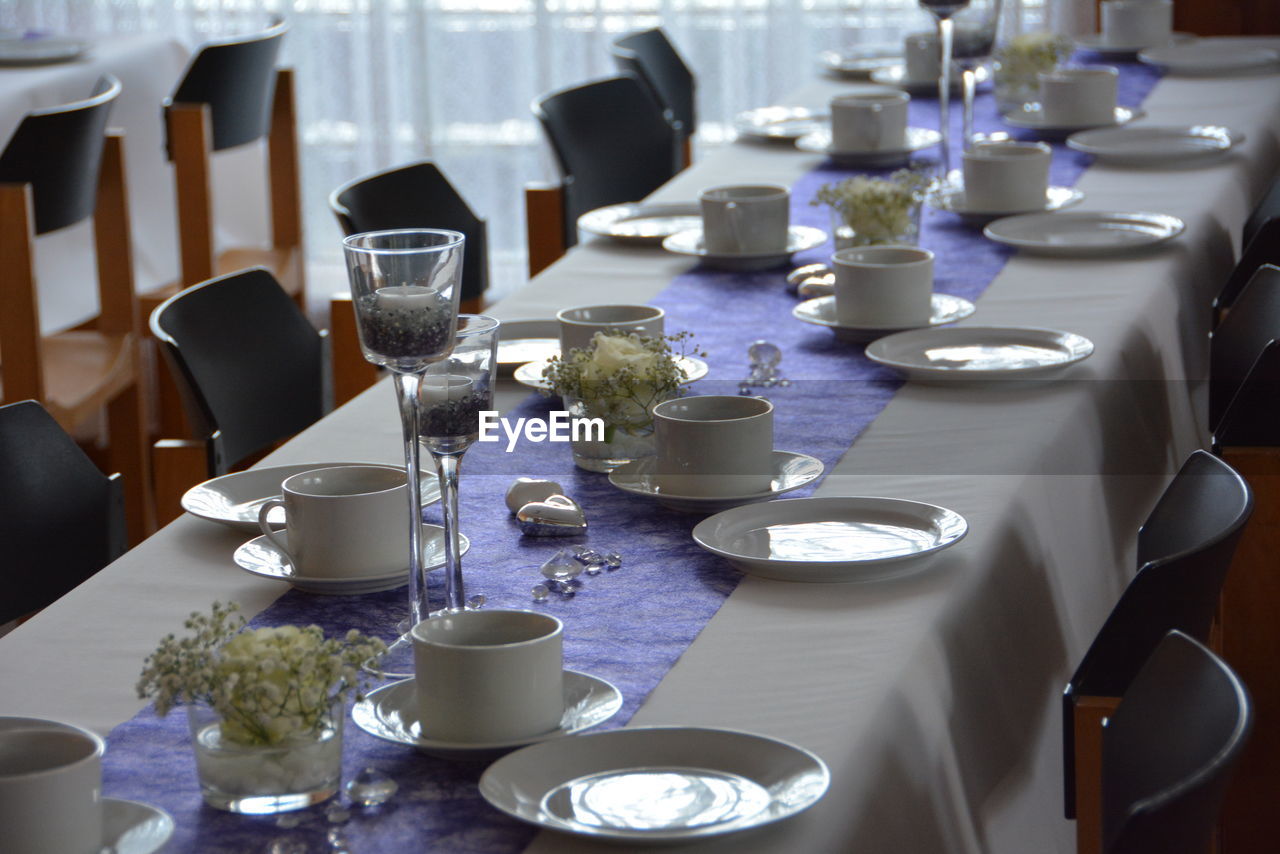 Cups and plates with candles arranged on table at restaurant