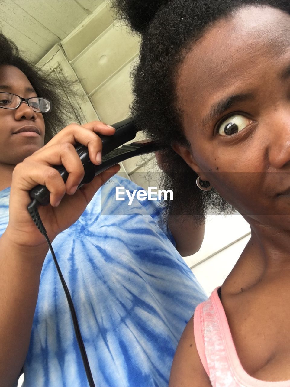 Daughter straightening mother hair at home