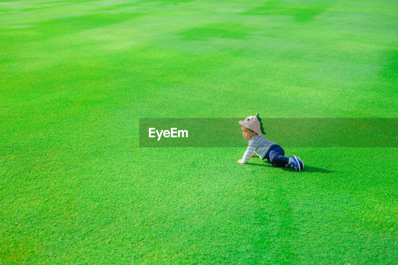 High angle view of boy crawling on grass at park