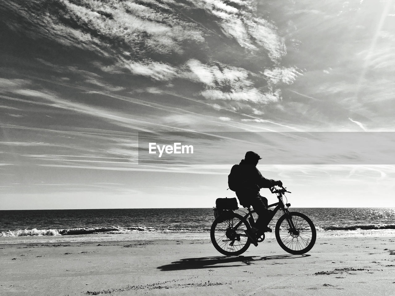 Side view of boy riding bicycle at beach