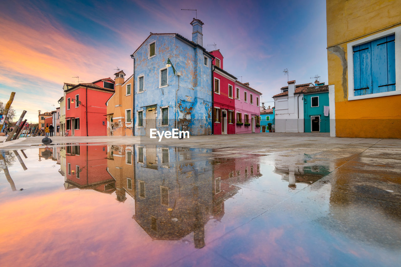 REFLECTION OF BUILDINGS IN PUDDLE ON STREET