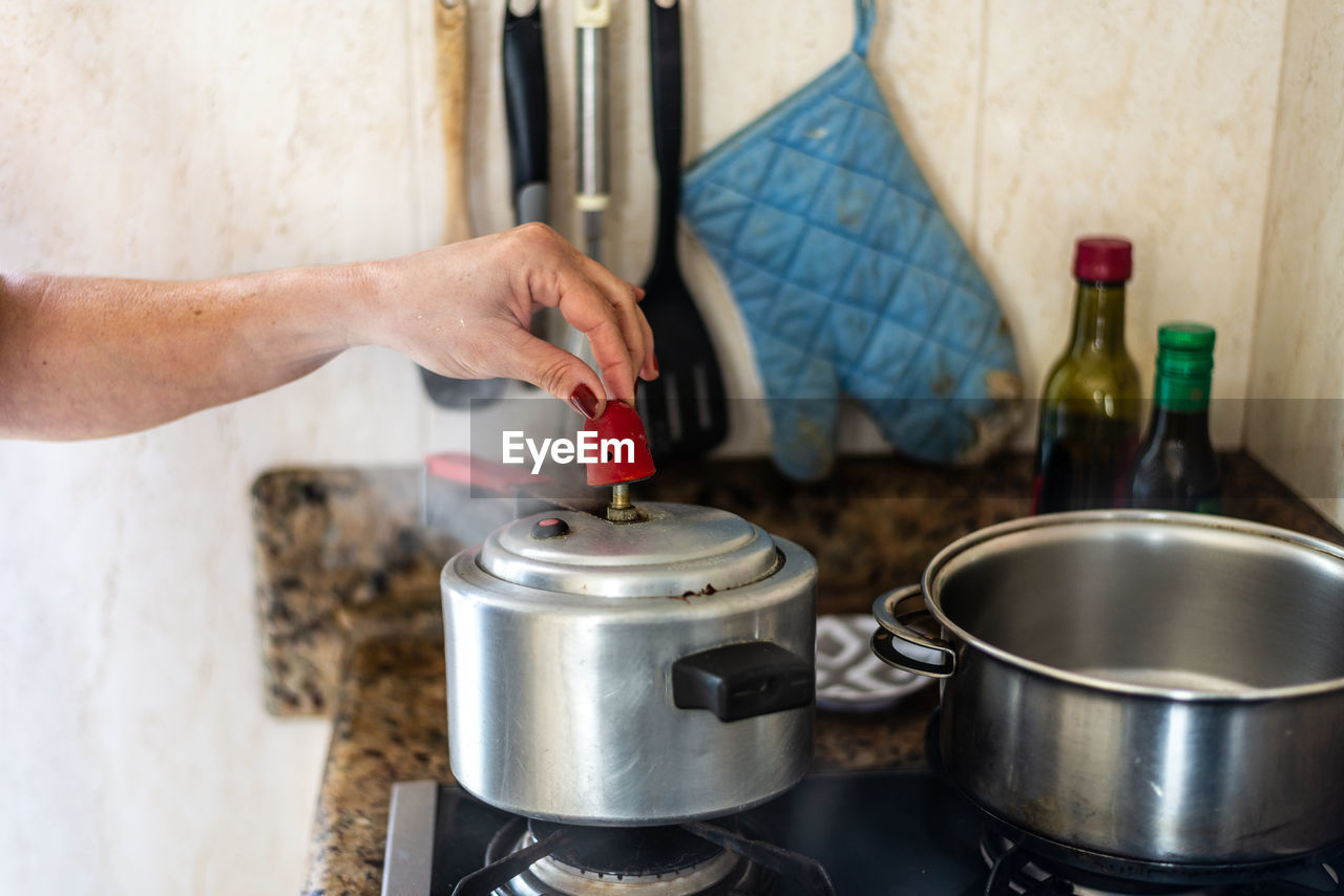 Young woman removing pressure from stainless steel pot.