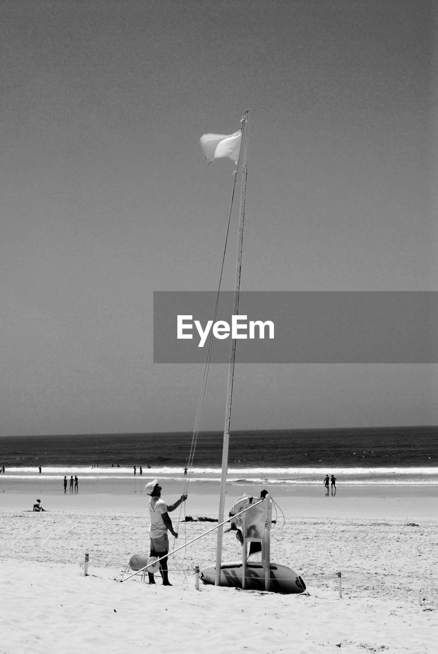 PEOPLE HOLDING BEACH AGAINST SKY