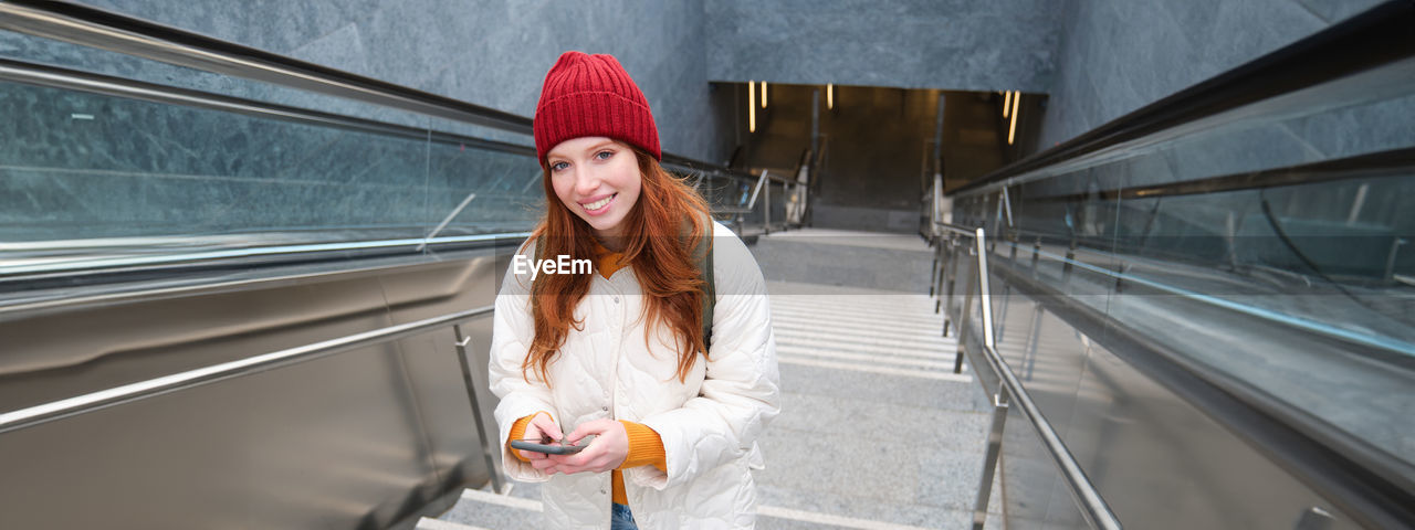low angle view of young woman standing on escalator