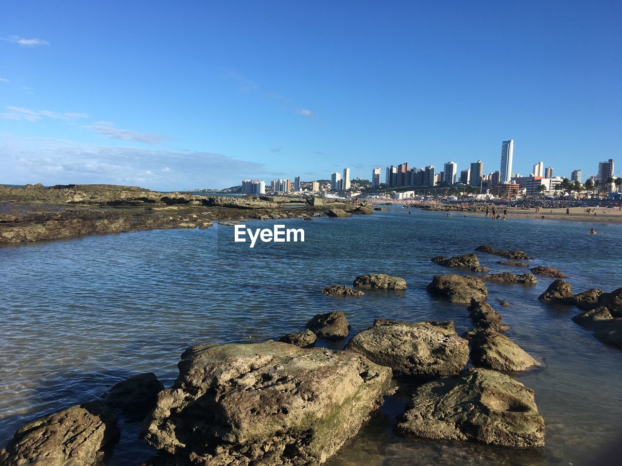 Scenic view of sea by buildings against blue sky