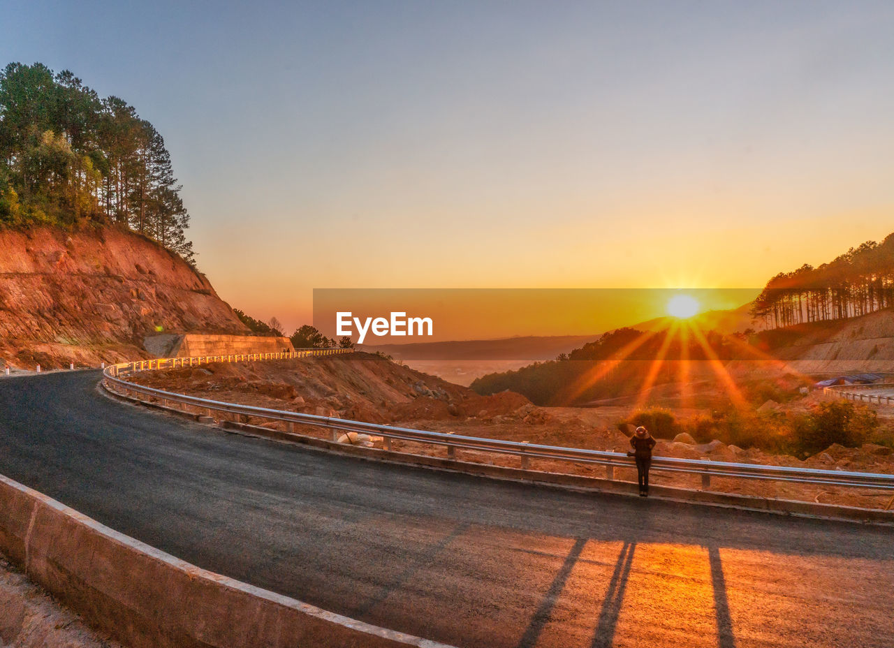 Road by mountains against clear sky during sunset