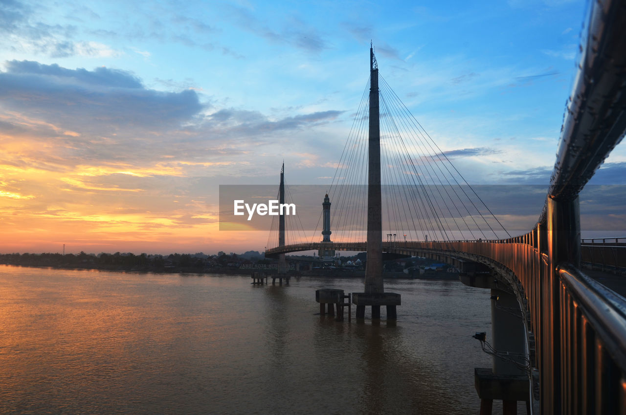 Bridge over sea against sky during sunset