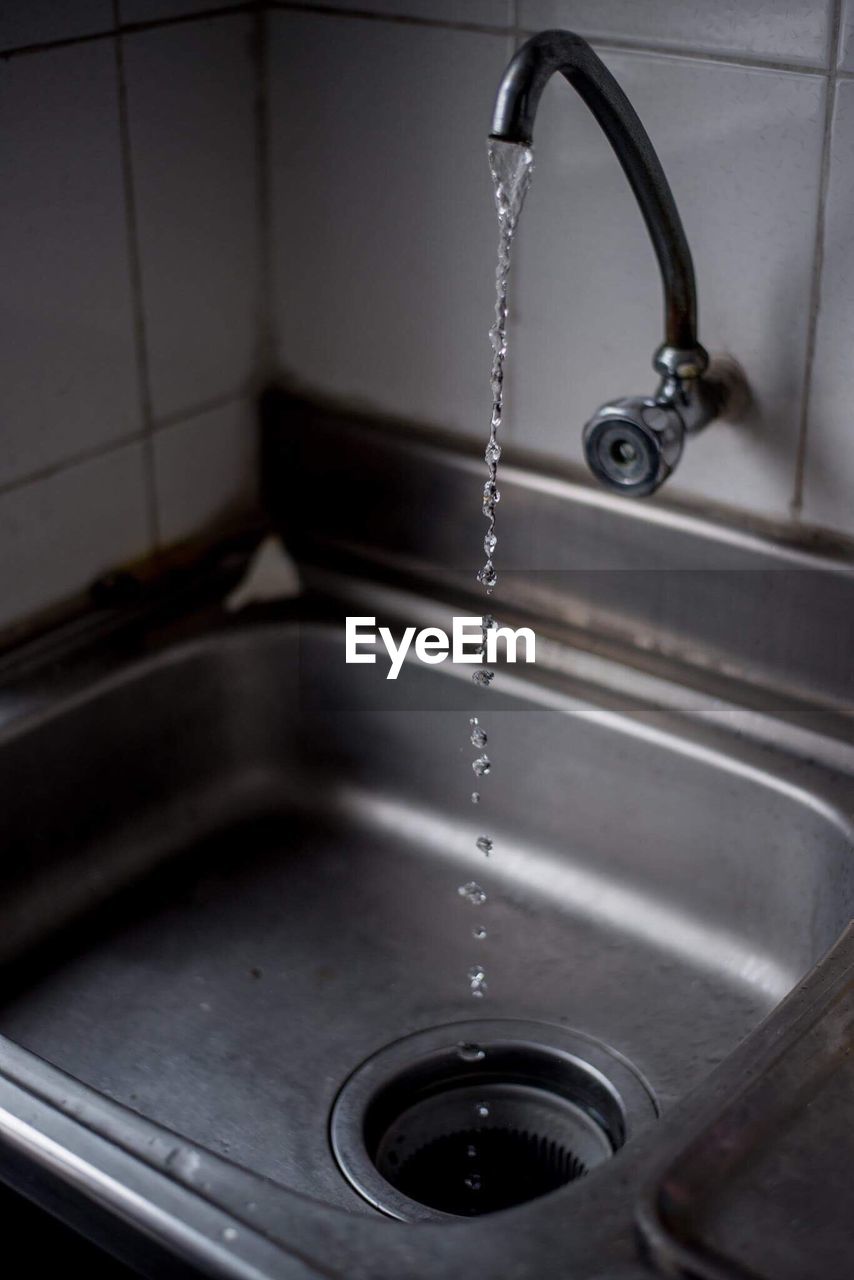 High angle view of water flowing form faucet at sink