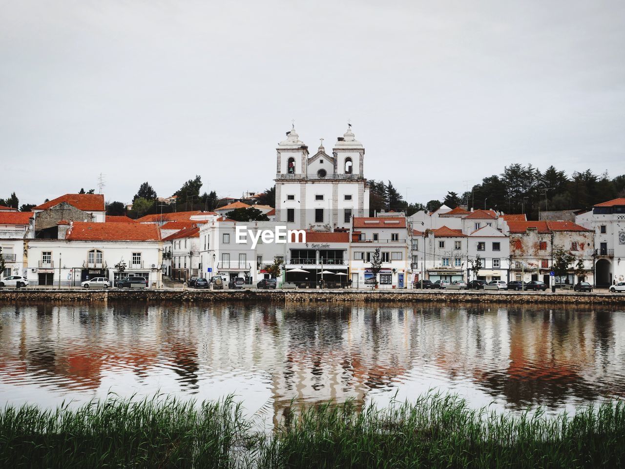 Buildings by river against sky in city