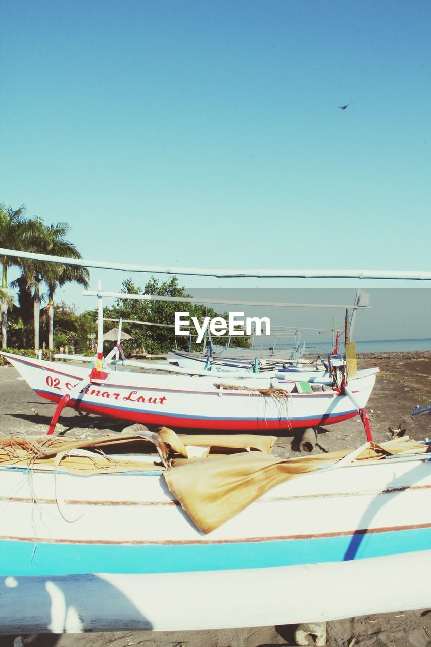 FISHING BOAT MOORED AT BEACH AGAINST CLEAR BLUE SKY