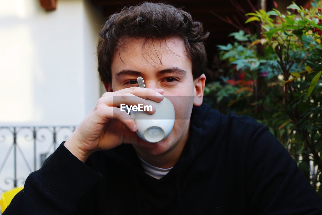 Portrait of young man drinking coffee at backyard