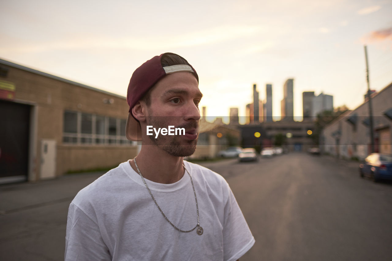 Young skateboarder exhaling cigarette smoke in downtown urban ar