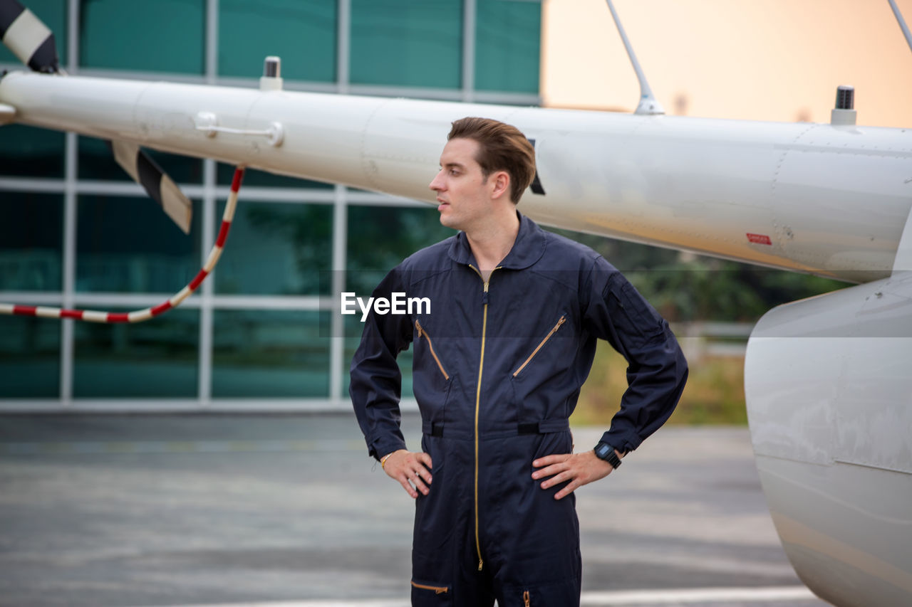 Young pilot standing by airplane