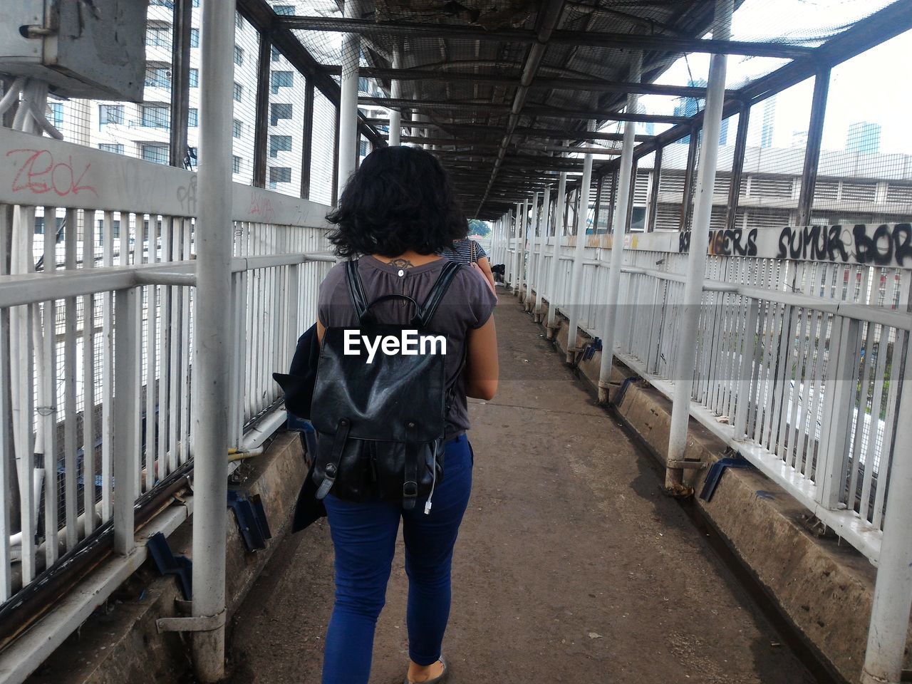 REAR VIEW OF MAN STANDING BY RAILING