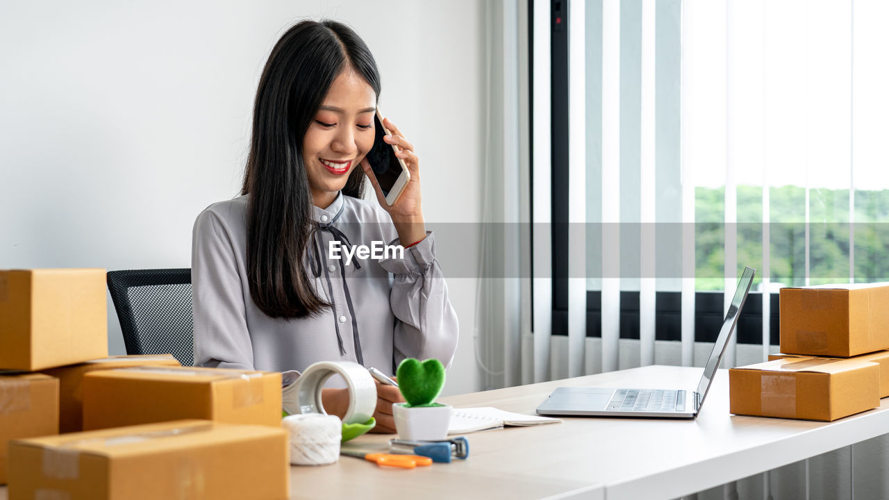portrait of young woman using mobile phone while sitting on table
