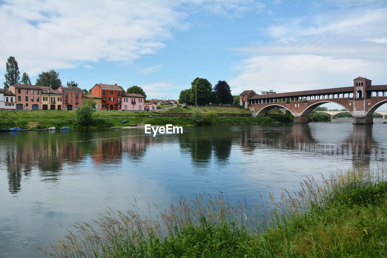 ARCH BRIDGE OVER RIVER BY BUILDING AGAINST SKY