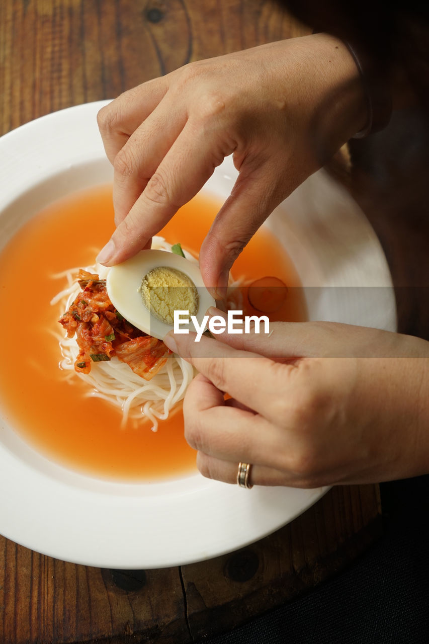 Cropped image of person having kimchi at restaurant