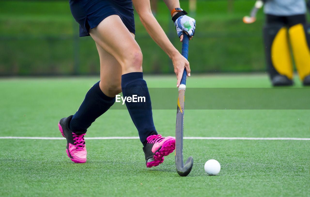 LOW SECTION OF WOMEN PLAYING WITH BALL ON GRASS