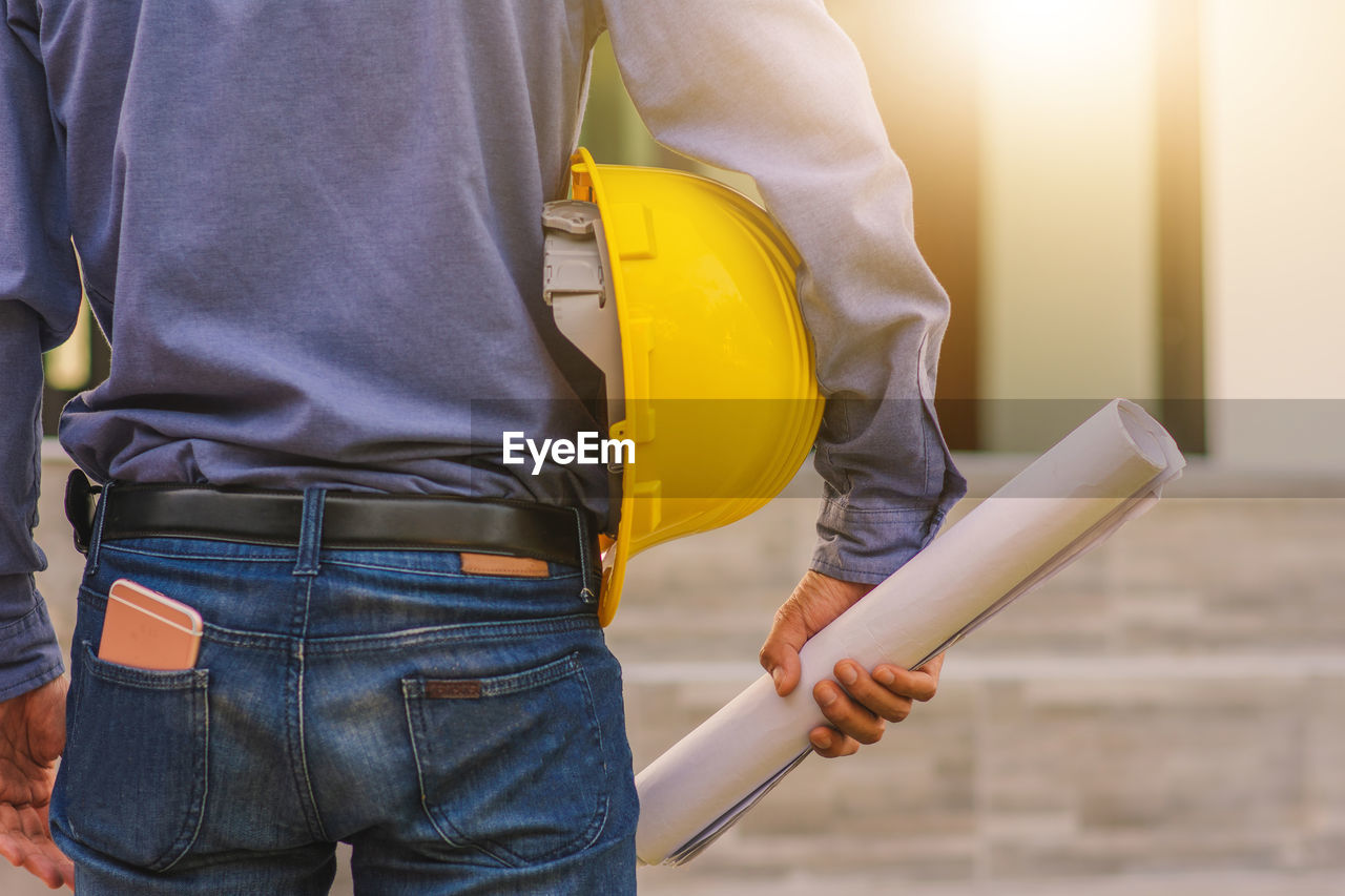 MIDSECTION OF MAN WORKING ON CONSTRUCTION SITE